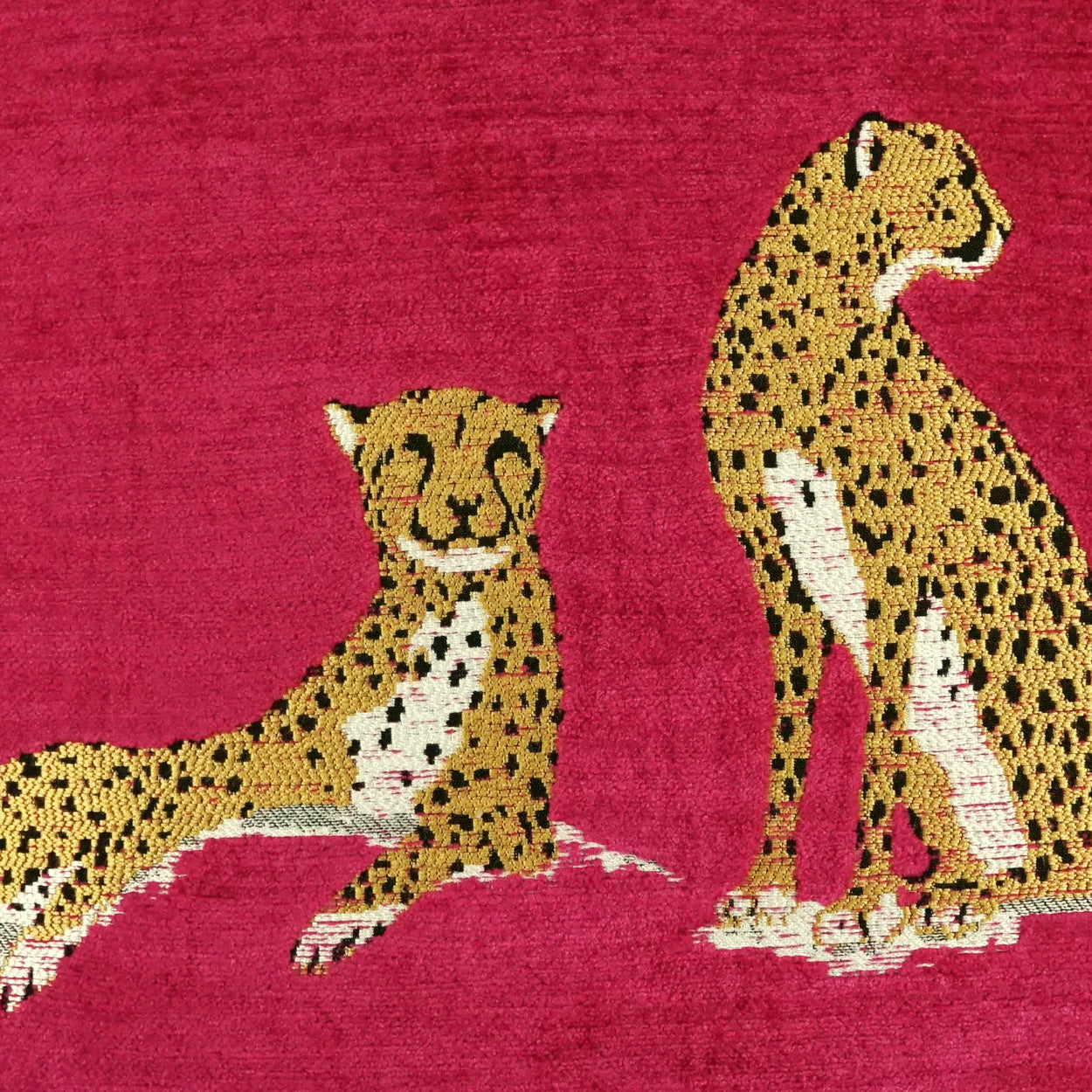 Magenta fabric featuring two gold leopard motifs with black spots; one reclining on the left, one standing on the right.