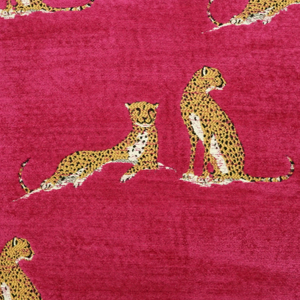 Magenta velvet-like fabric with golden leopard silhouettes in a playful wildlife pattern.