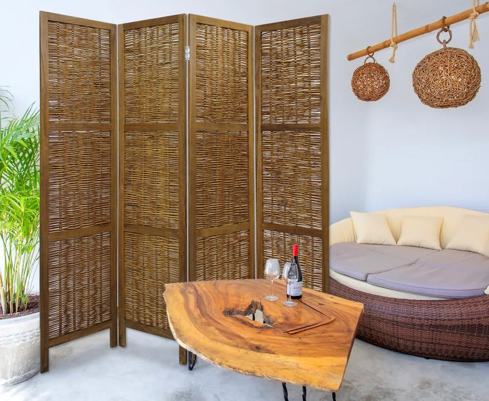 Four-panel woven rattan room divider with dark wood frame in a lounge beside a live-edge wood coffee table and wicker daybed.