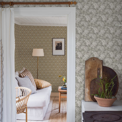 Vintage-style living room seen through a white-trim doorway; grey stone-look wallpaper, wicker chair, white sofa & a plant on wood boards.