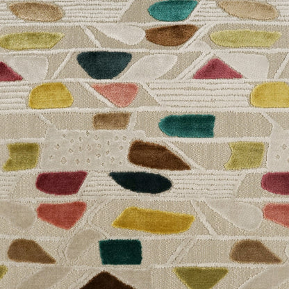 Beige woven pillow with multicolor abstract shapes in yellow, teal, green, pink and brown; modern geometric pattern.