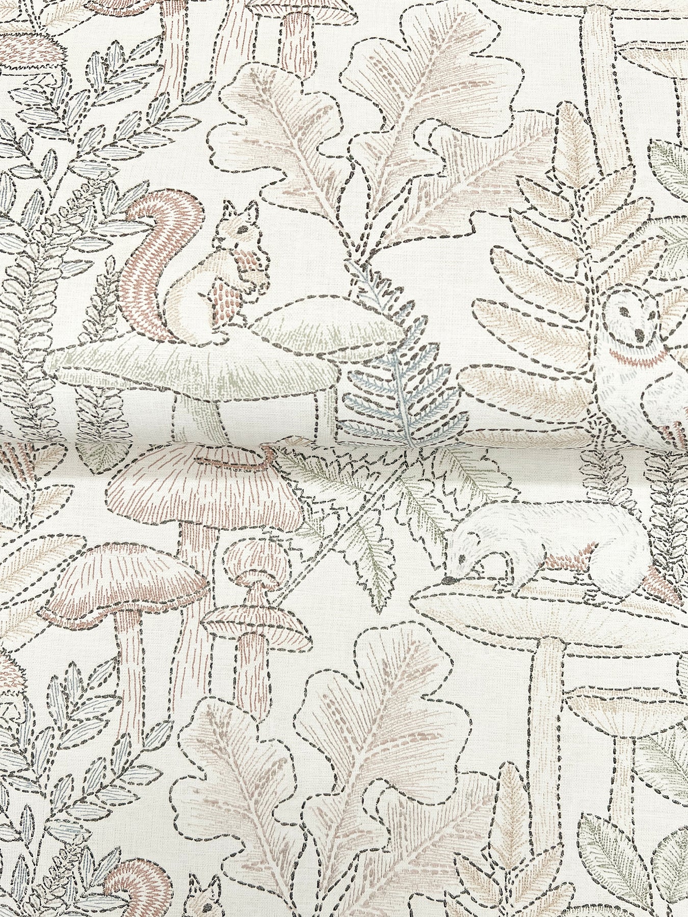 Embroidered, line-drawn woodland pattern on fabric with squirrels, mushrooms and leaves in soft beige and taupe.