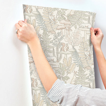 Beige-gray botanical print fabric wall panel held by hands; fern and leaf motif in neutral tones.