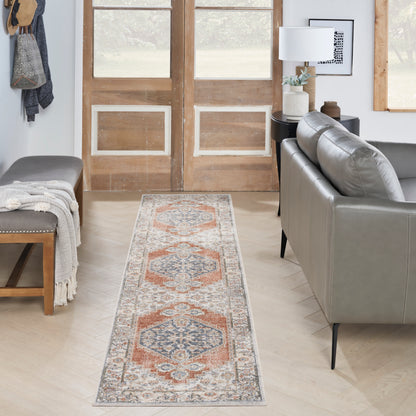 Long runner rug with orange, blue and cream geometric pattern on light wood floor beside a grey sofa in a modern living room.