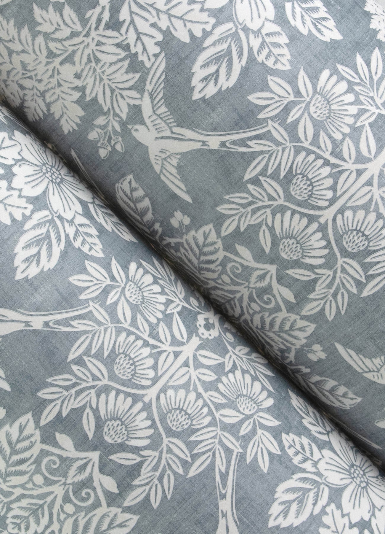 Close-up of blue-gray fabric with a white floral and leaf pattern.