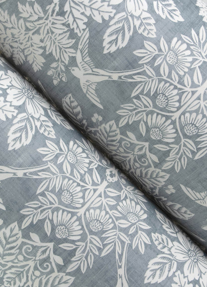 Close-up of blue-gray fabric with a white floral and leaf pattern.