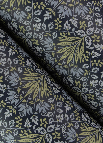 Close-up of navy fabric with olive-green and light-blue botanical leaves; folded, textile print for clothes or decor.
