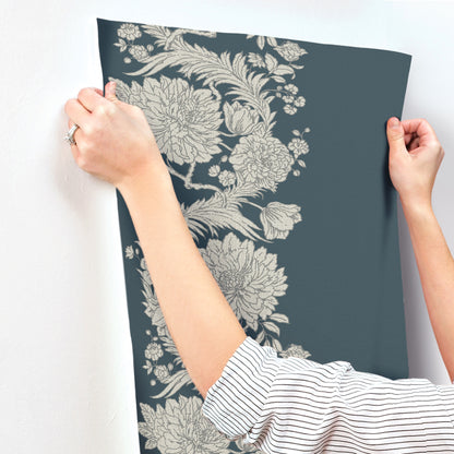 Dark blue wall panel with beige floral print, held by hands in a striped sleeve.