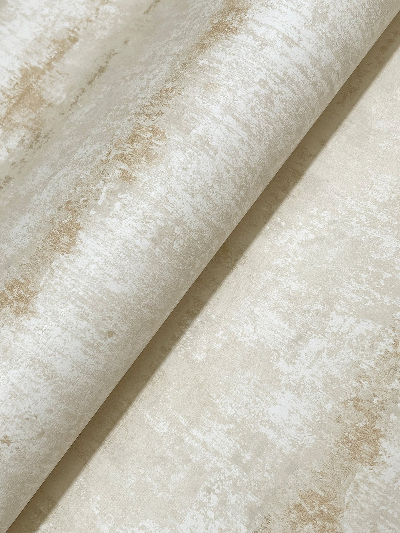 Beige distressed wallpaper with ivory marbling, rolled sheet texture and soft weathered finish.