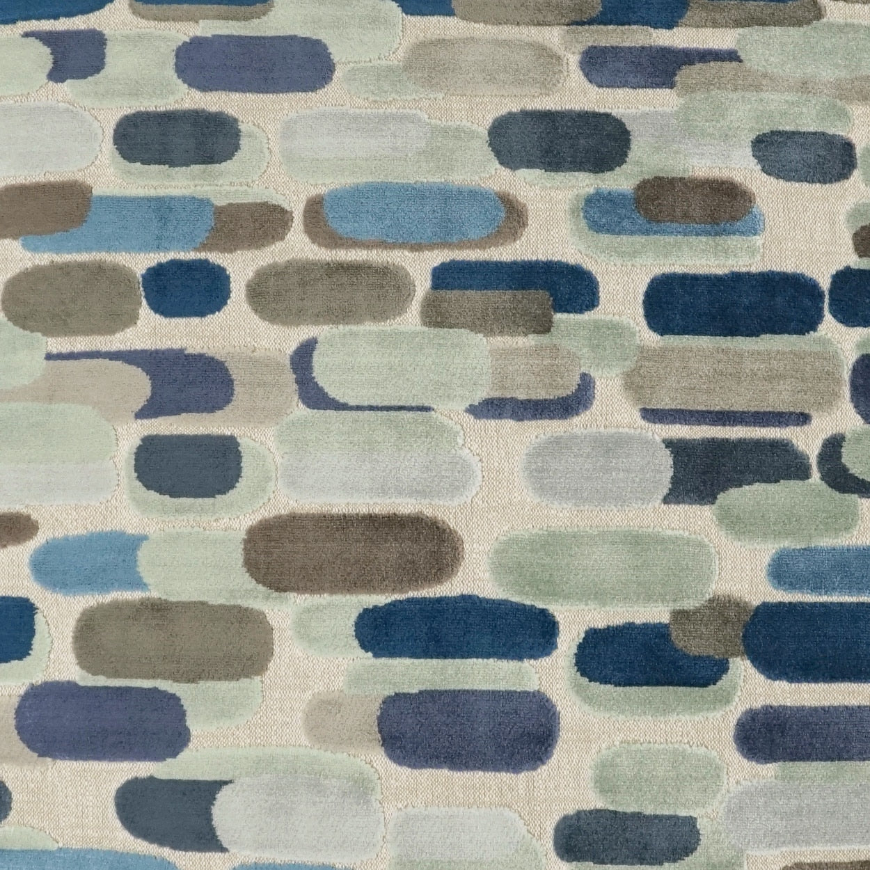 Soft area rug with rounded pill shapes in blues, grays, and sage on a light beige background.