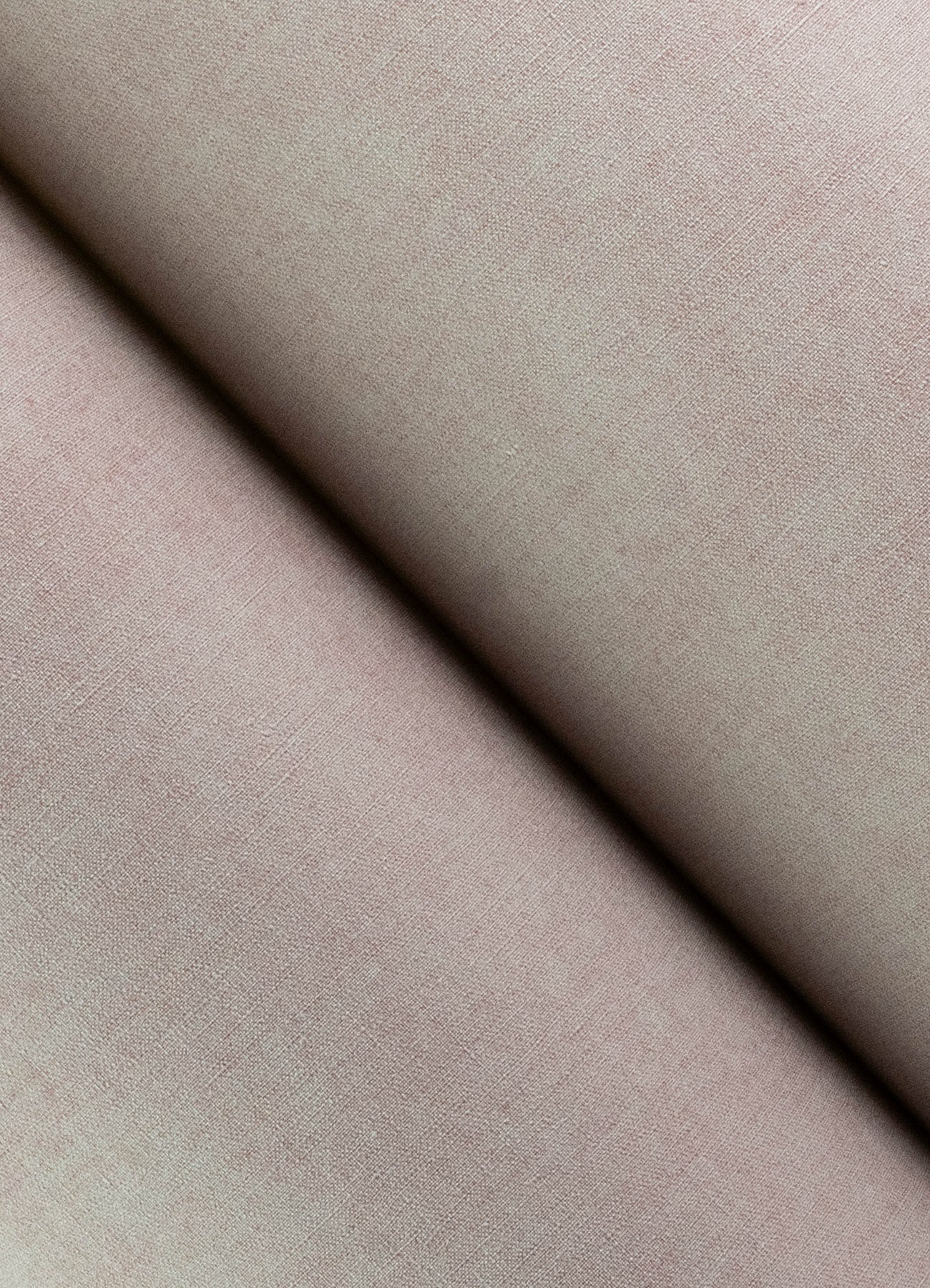 Lavender faux-linen wallpaper close-up showing a diagonal fold and soft matte texture