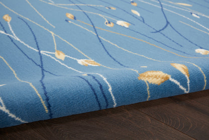 Blue plush area rug with white and mustard abstract lines on dark wood floor.