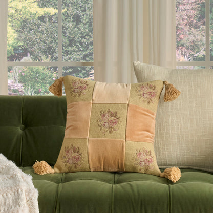 Patchwork square cushion with floral embroidery & tassels on a green tufted sofa; cream, peach & sage panels.
