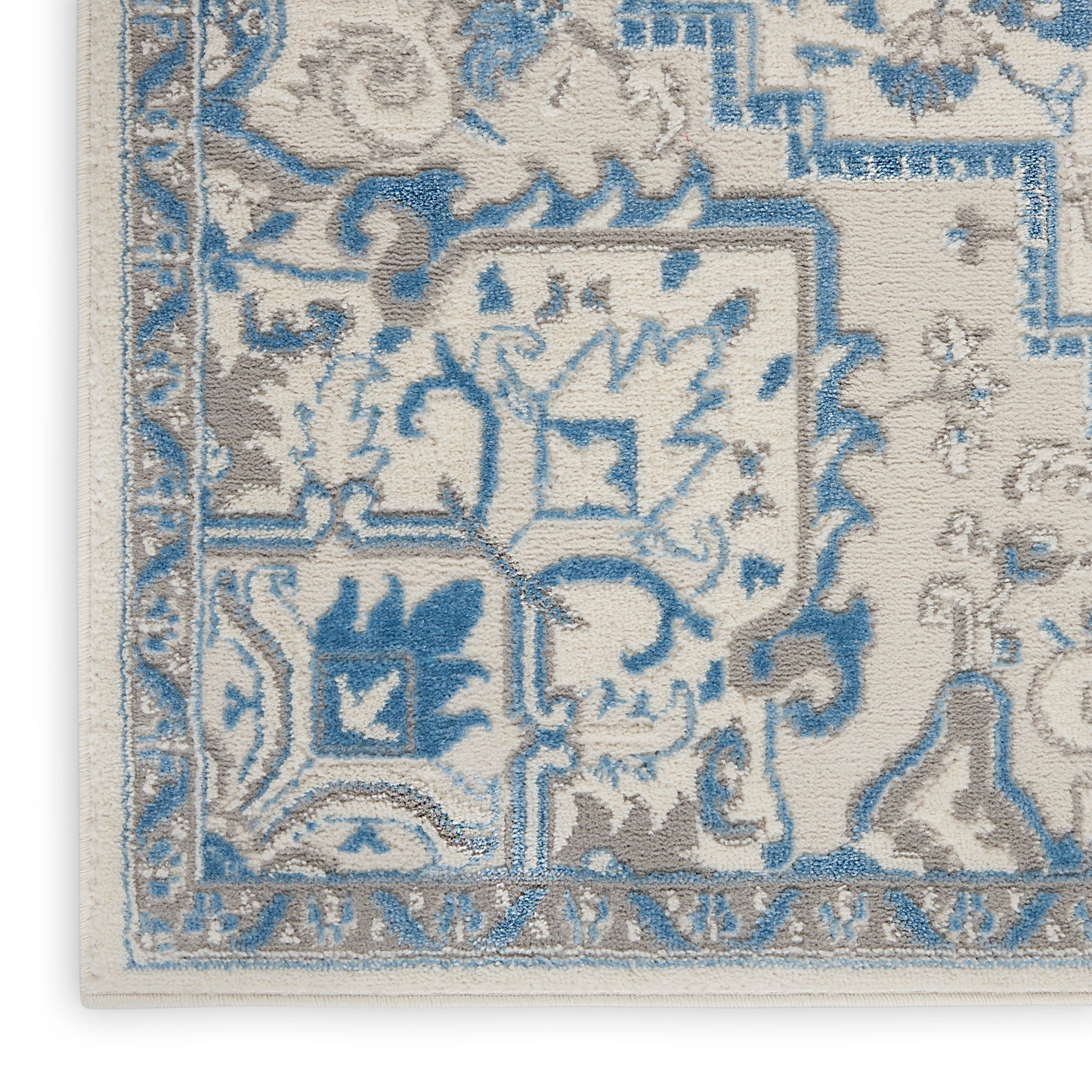 Cream and blue Bohemian area rug with floral motifs, ornate border and fringe edge.