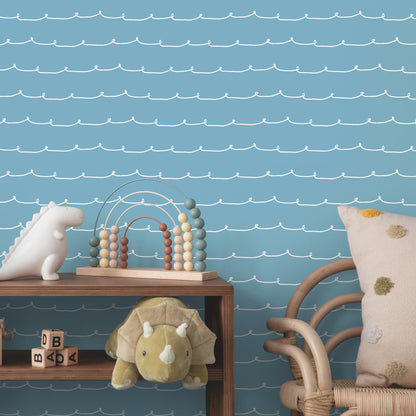 Soft blue striped wallpaper with wiggle-line pattern; wooden shelf with plush lion, bead abacus, pastel arches, rattan chair, polka-dot pillow.
