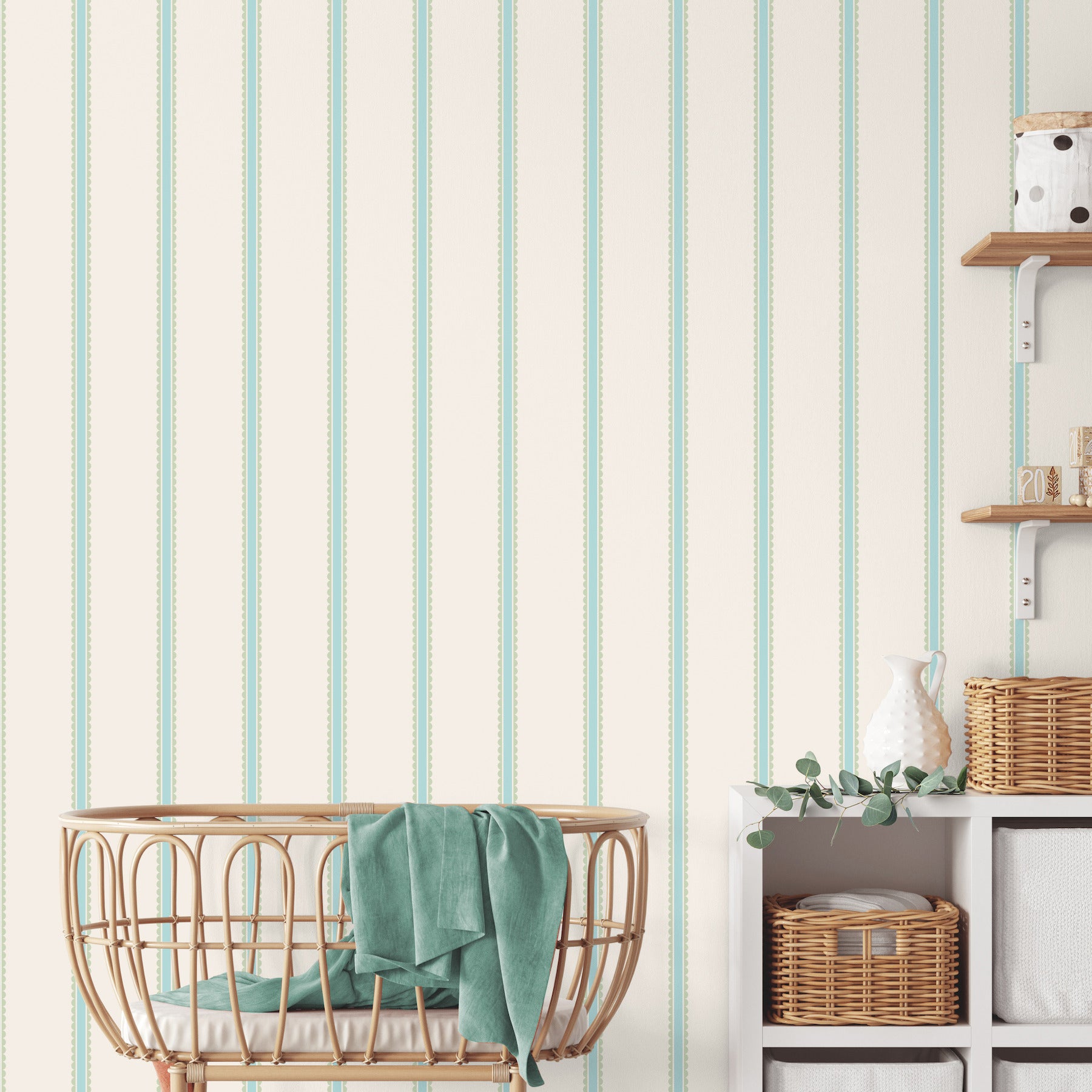 Natural rattan baby bassinet with teal blanket on cream wall with mint-striped wallpaper; wicker baskets and cubby shelves.