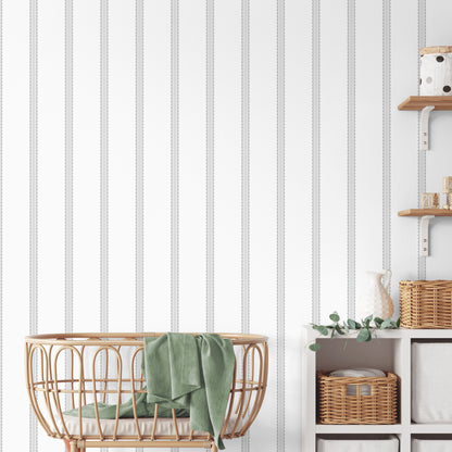 Grey striped wallpaper with a scalloped motif shown in a room setting.