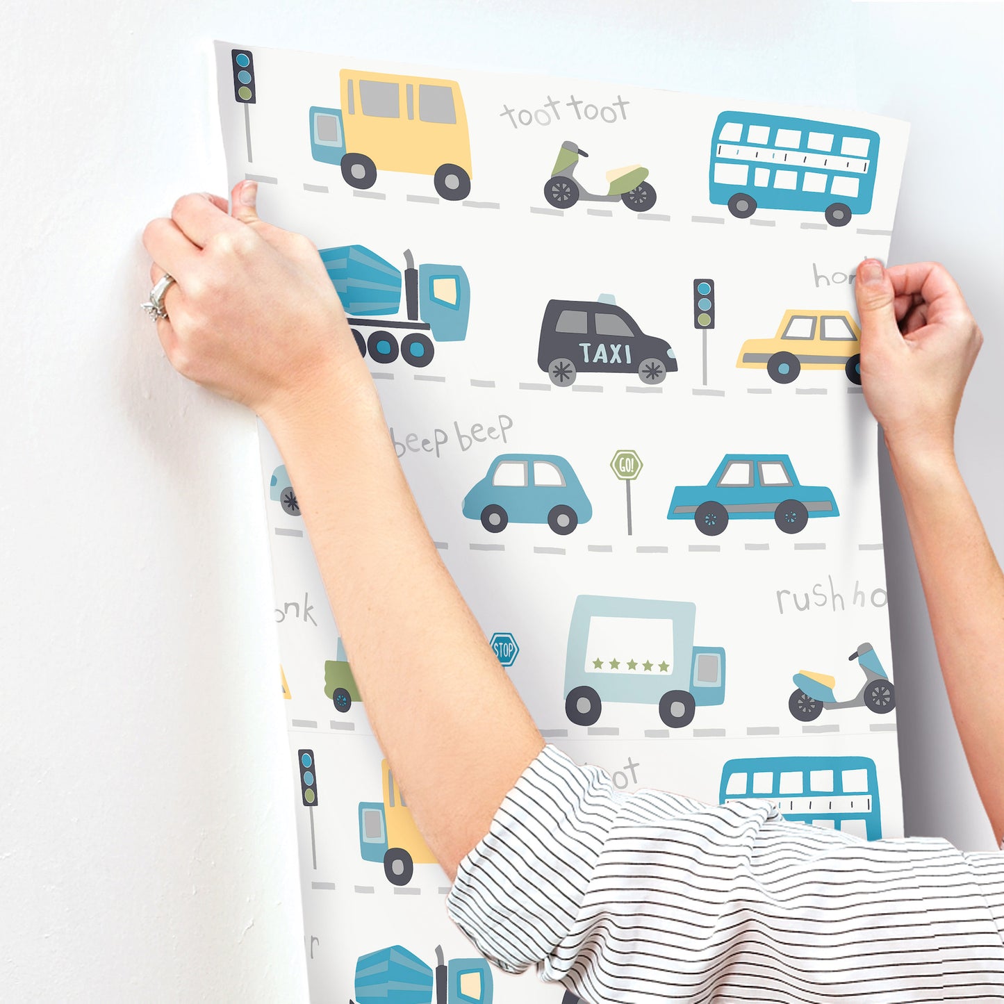 Colorful vehicle pattern sheet with buses, cars, trucks and motorcycles, held by hands.