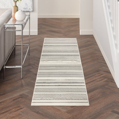 Neutral striped hallway runner rug with geometric patterns in cream, gray and beige on dark wood floor.