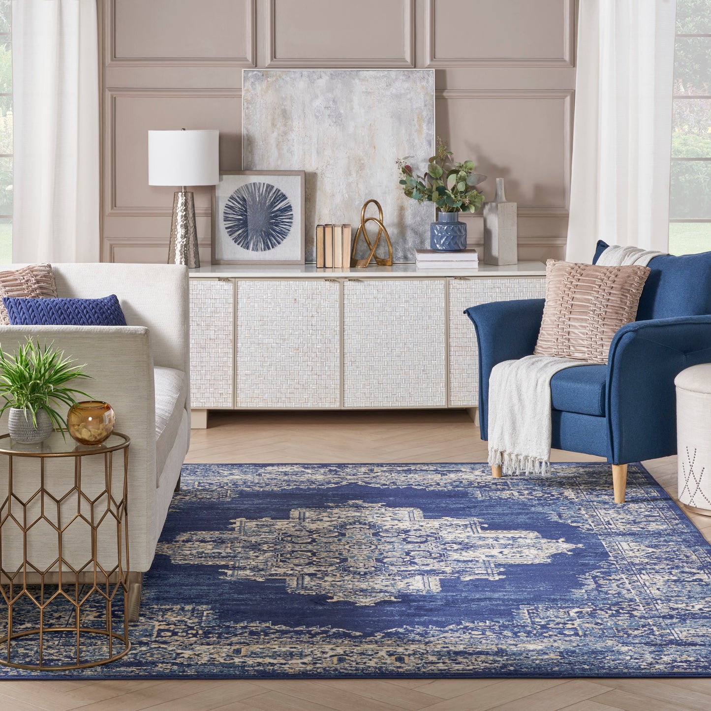 Taupe paneled walls, white woven sideboard, navy distressed rug, beige sofa, blue accent chair.