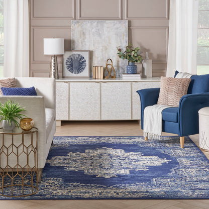 Taupe paneled walls, white woven sideboard, navy distressed rug, beige sofa, blue accent chair.