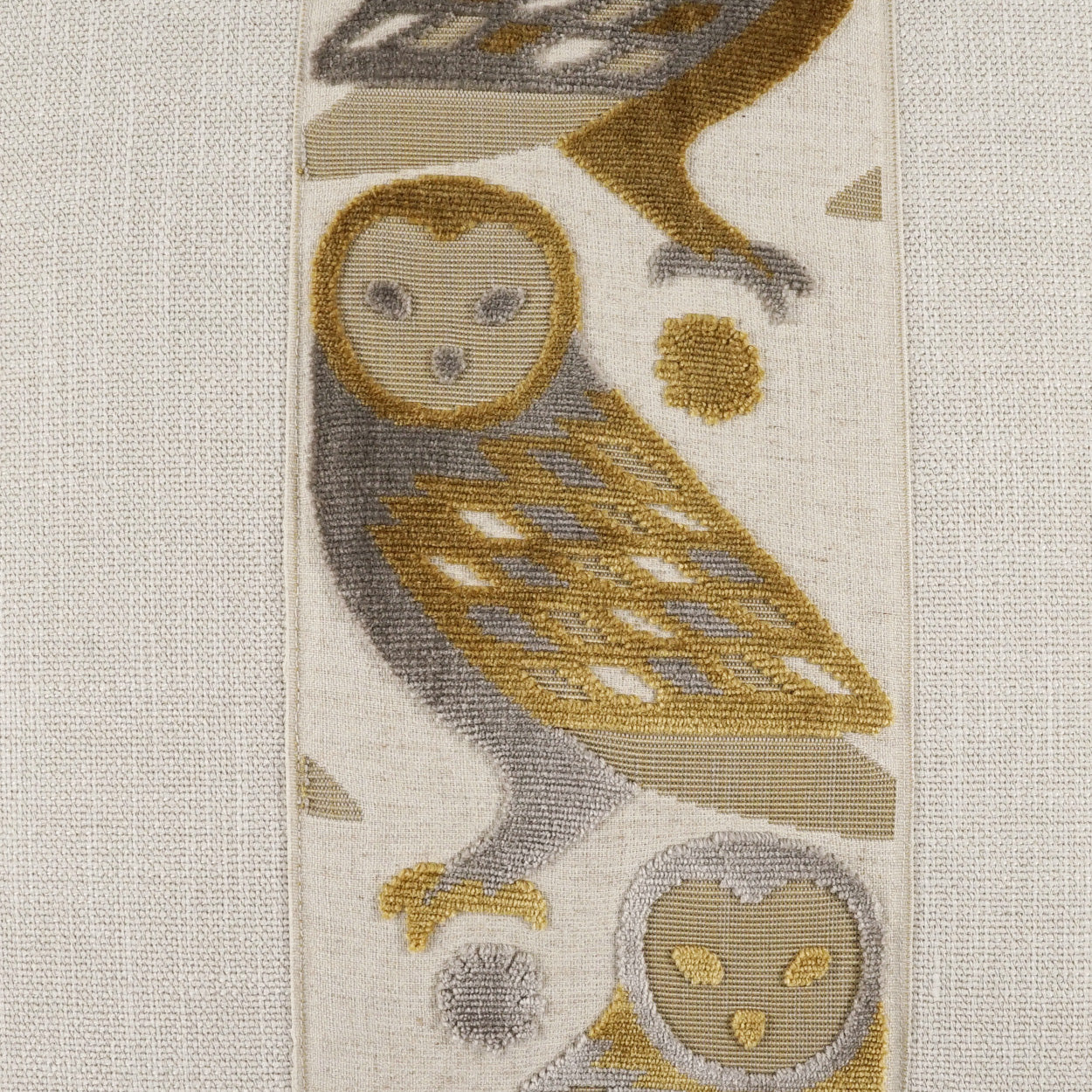 Pillow featuring beige, gray & gold owl motifs on a tapestry-style woven fabric.