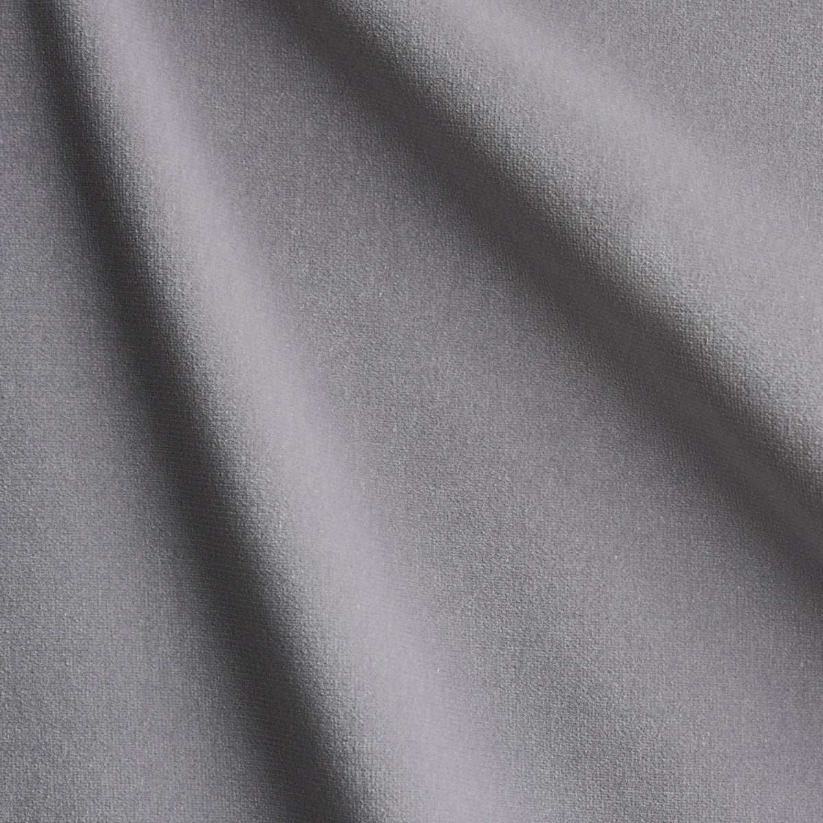 Gray velvet fabric with soft drape and subtle texture, diagonal folds; versatile for apparel or upholstery.