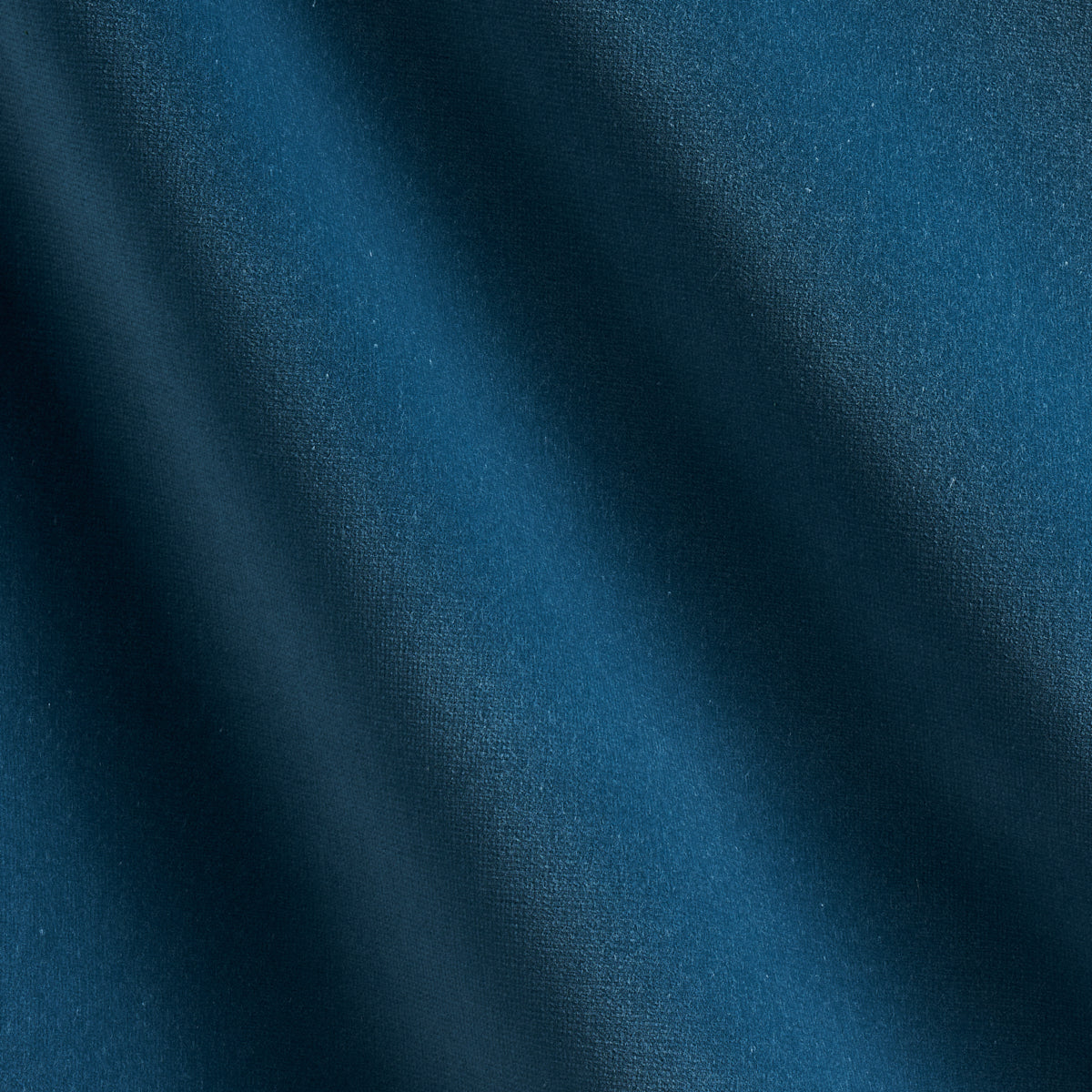 Close-up of dark teal velvet fabric with diagonal folds and smooth texture.