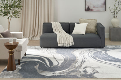 Modern living room with dark gray sofa, white cushions, beige throw, white chair, round wood side table, marble swirl rug.