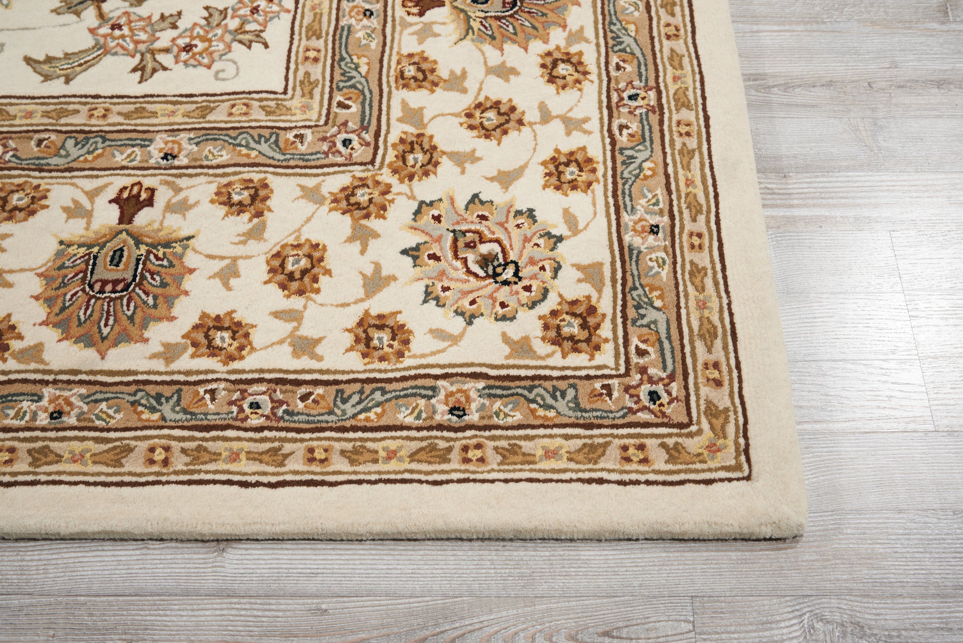Cream-beige oriental rug with floral motifs and ornate borders in brown and blue on a light wood floor.