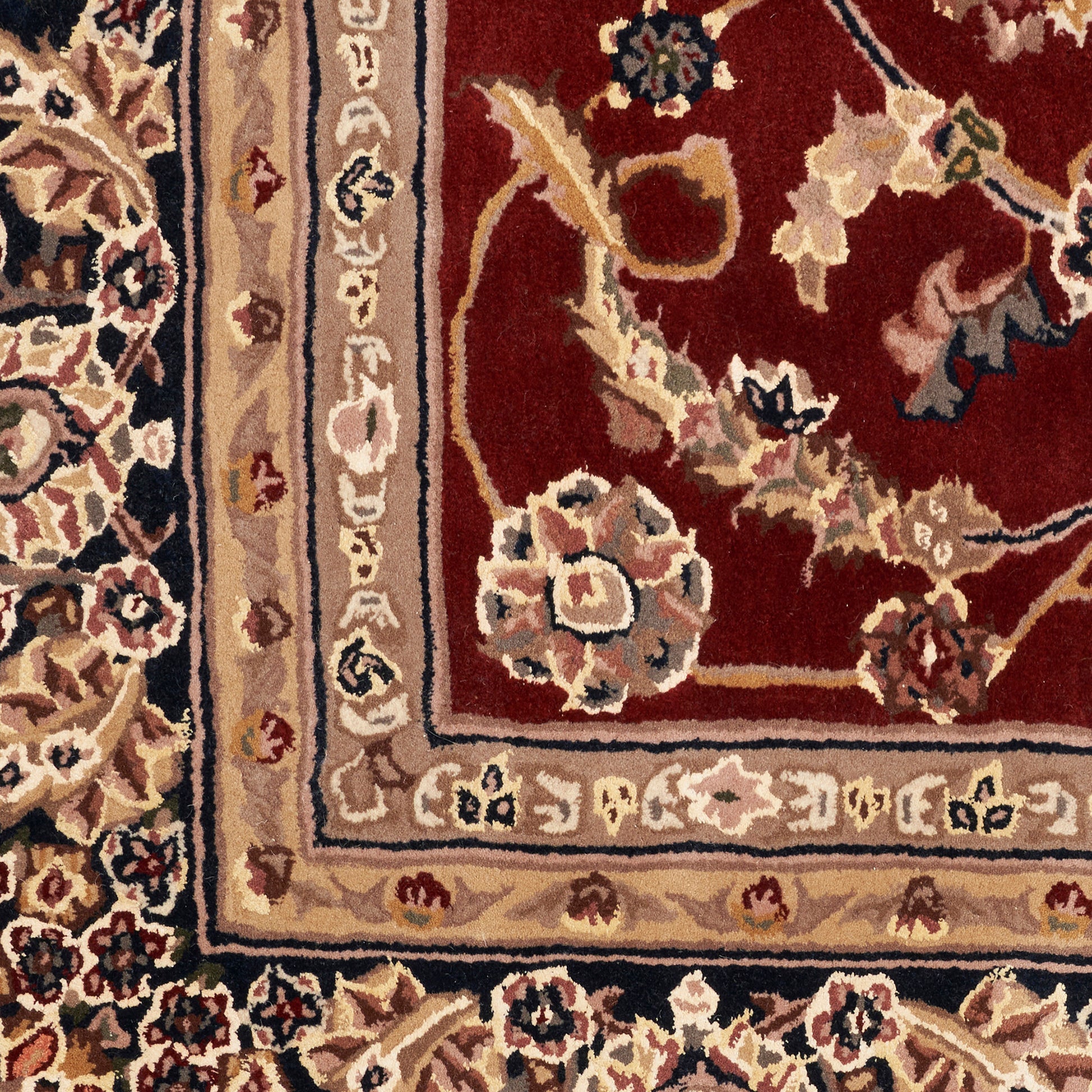 Close-up of an ornate Persian-style rug with burgundy field and beige-cream floral border.