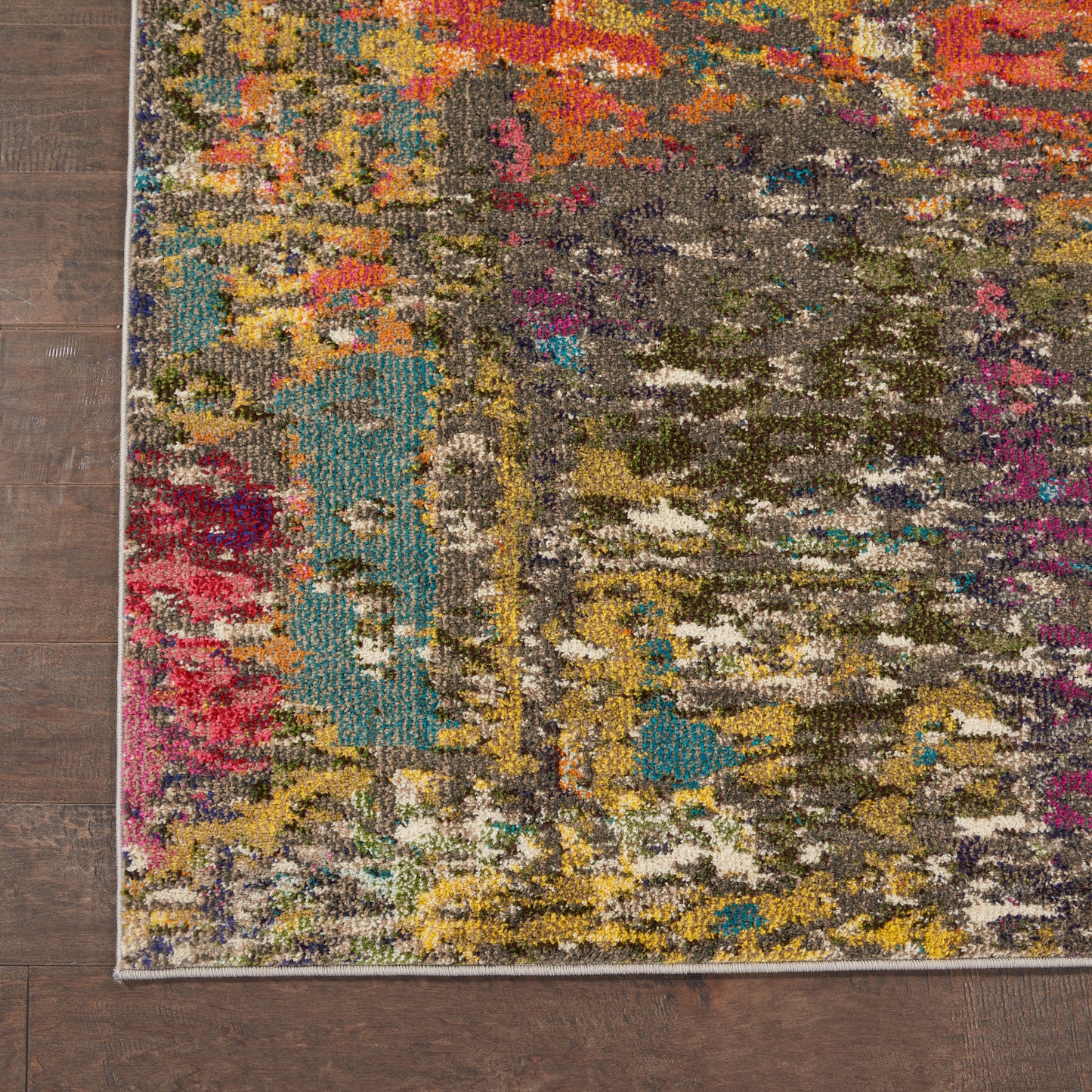 Colorful abstract area rug on dark wood floor; teal, pink, yellow and gray patches, rectangular with a light border.