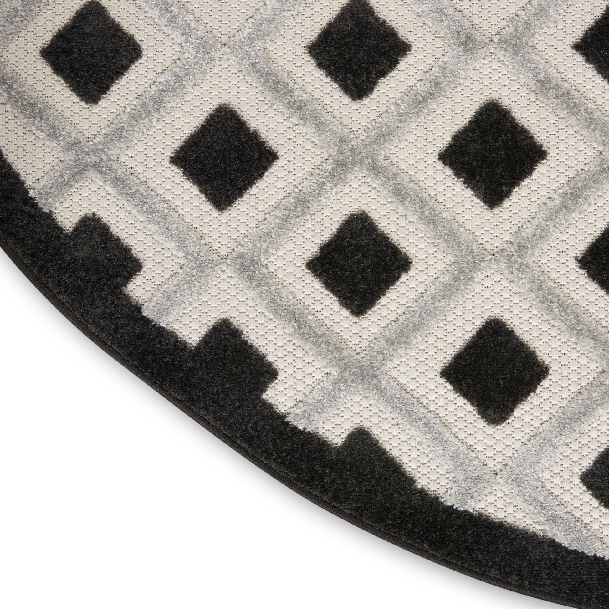 Geometric round rug with a black diamond pattern on light grey, dark border; modern soft floor decor.