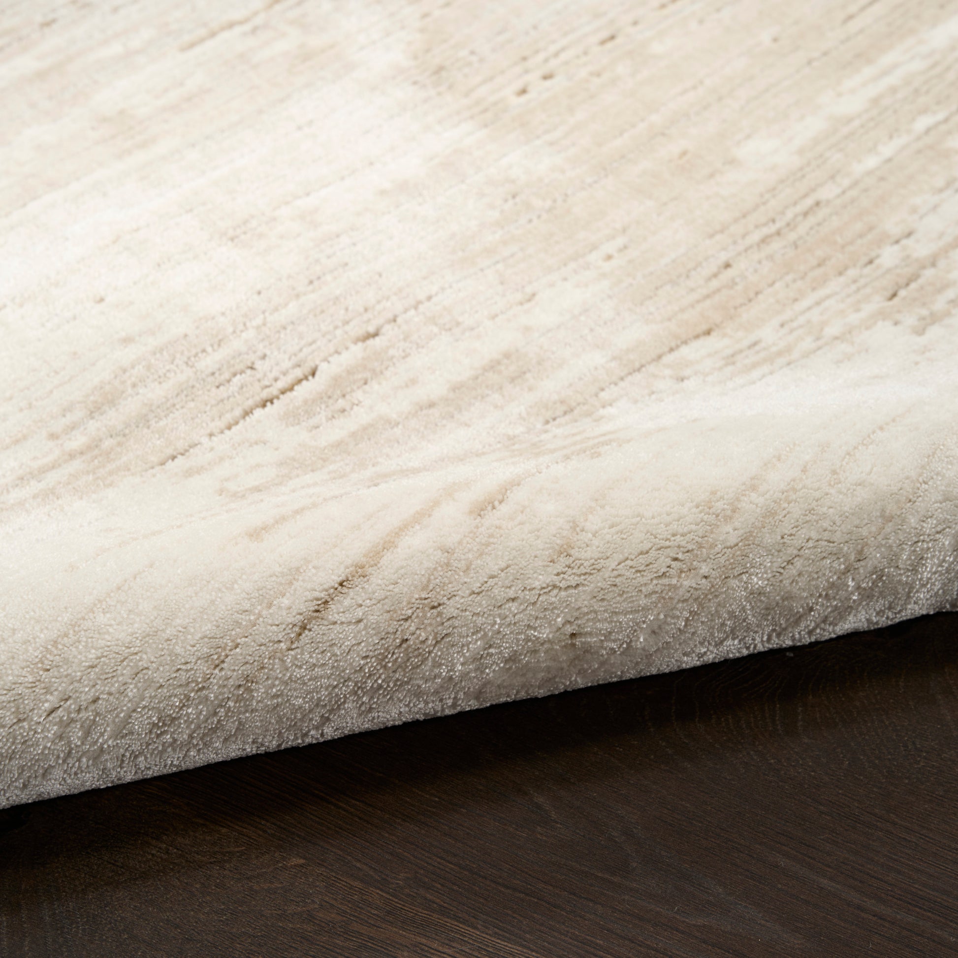 Cream beige shag runner rug with soft plush pile and rolled edge on dark wood floor.
