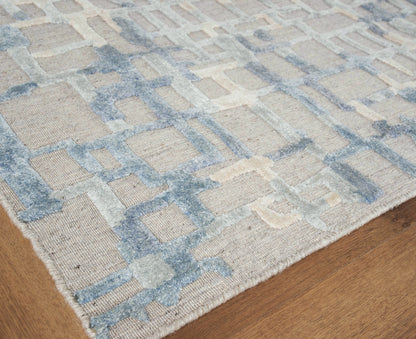 Soft beige rug with pale blue geometric square motifs on wood floor.