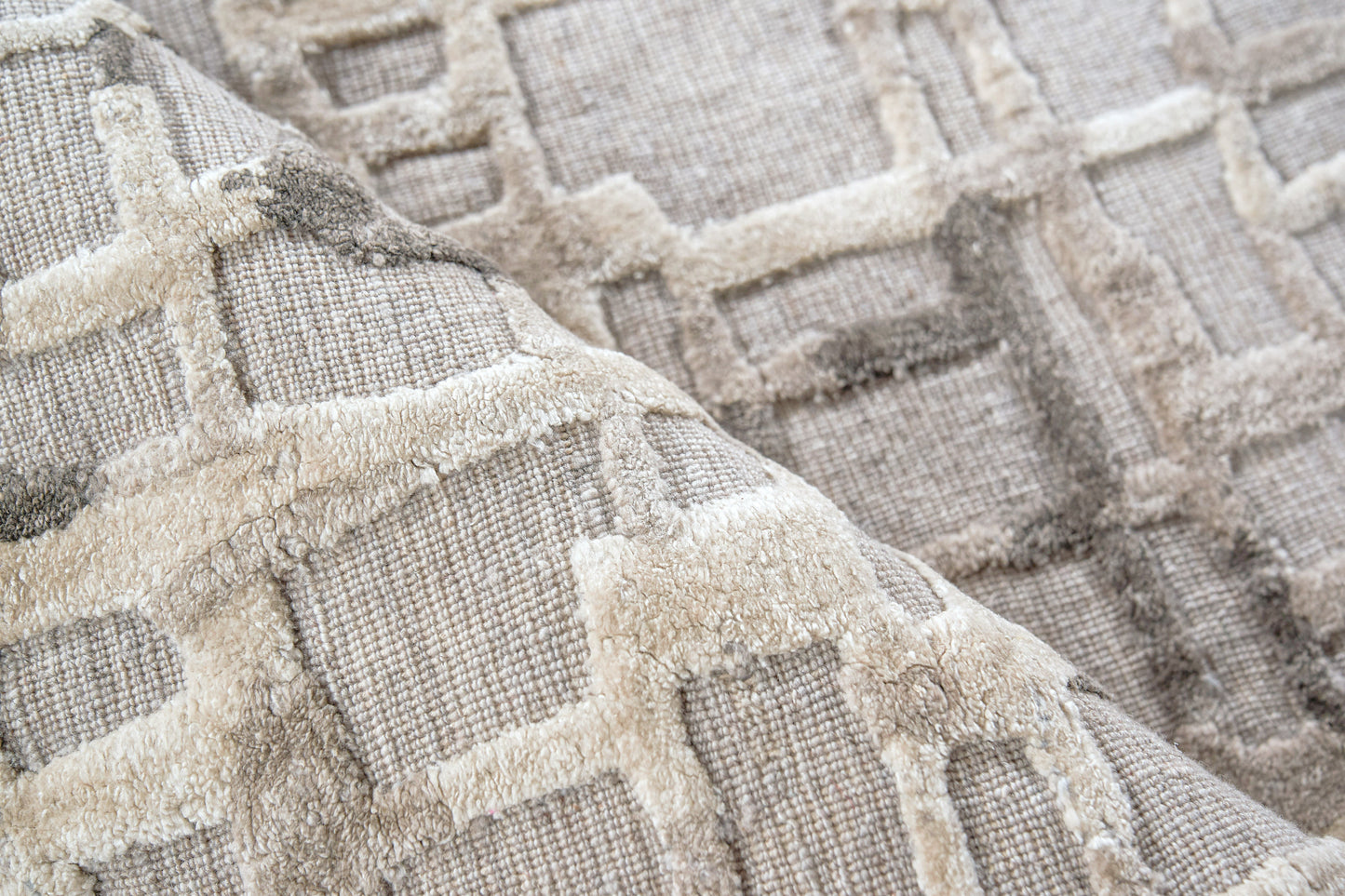 Beige woven textile rug with plush raised geometric grid pattern in cream and taupe tones.