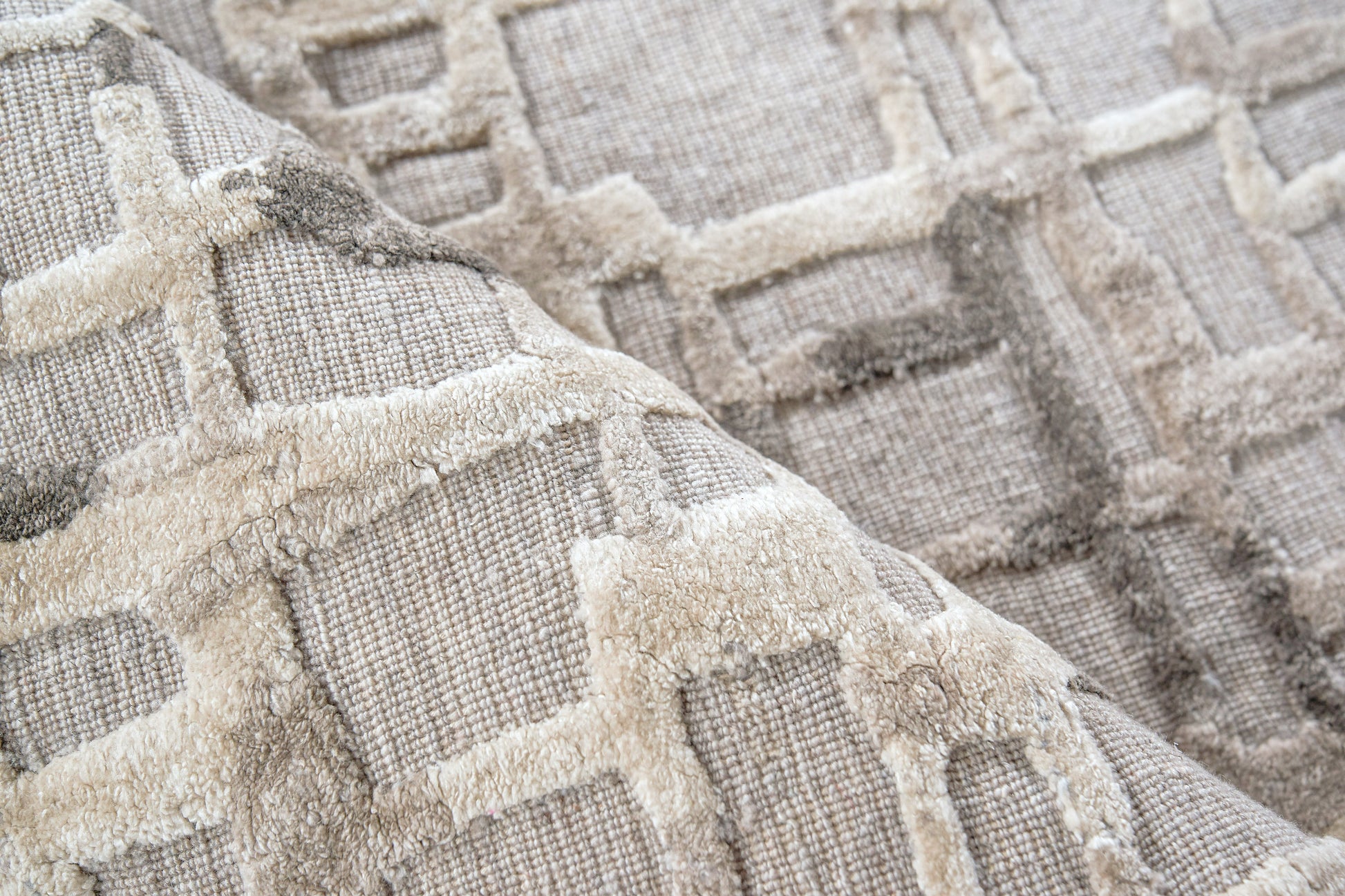 Beige woven textile rug with plush raised geometric grid pattern in cream and taupe tones.