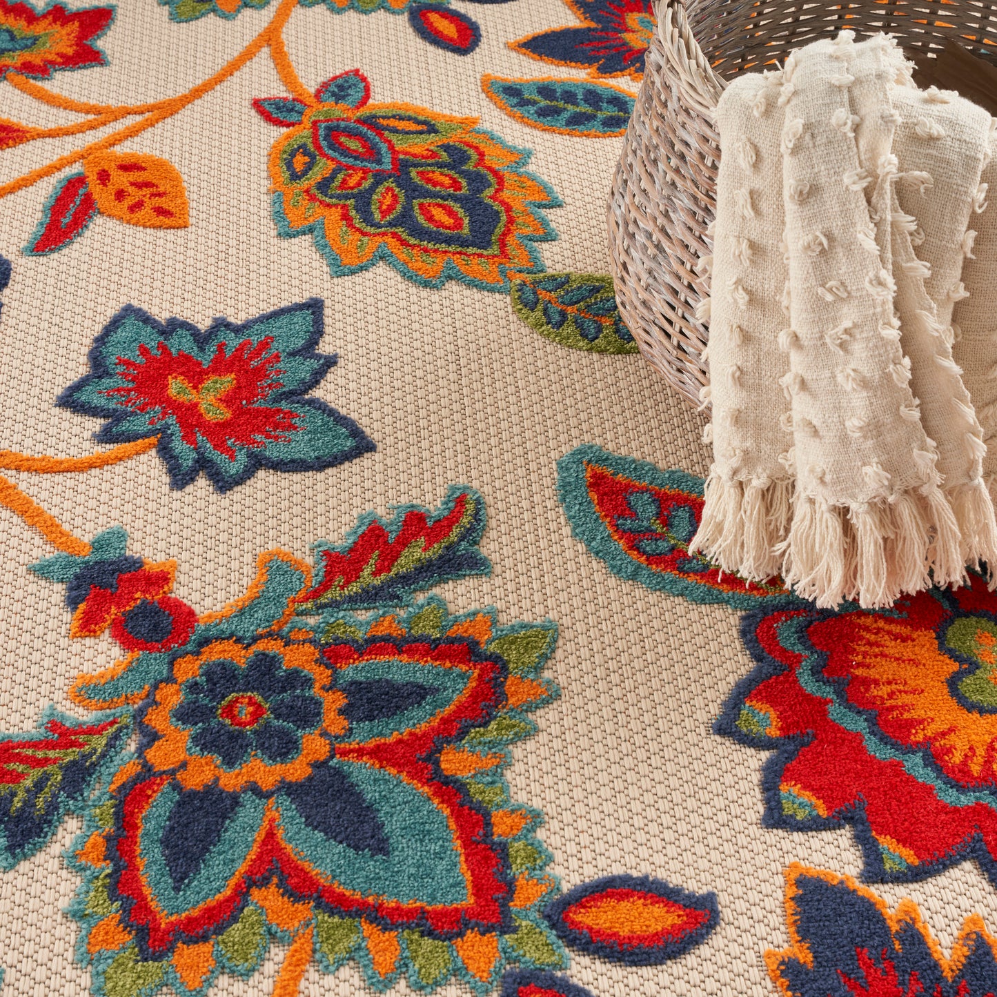 Colorful floral patterned rug in beige with teal, orange & red flowers.