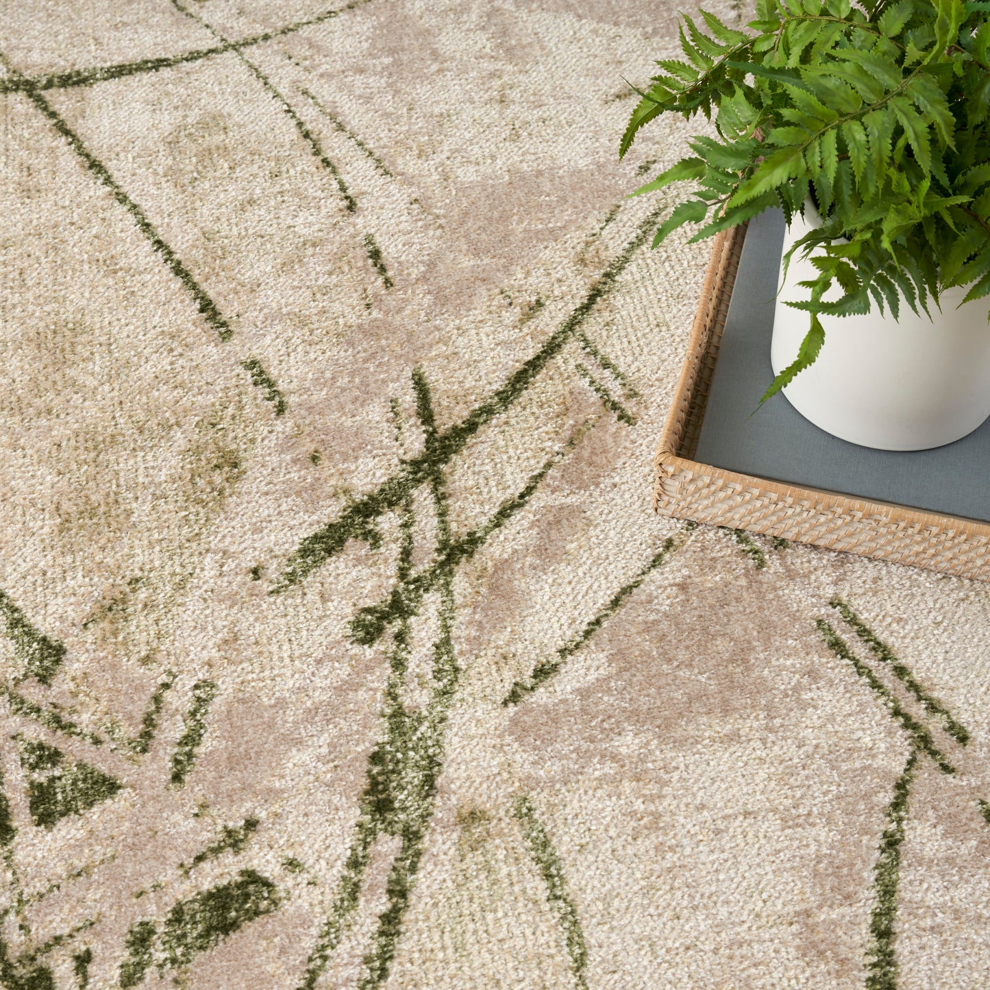 Beige rug with dark green abstract lines; wooden tray holding a white pot of fern on the edge.