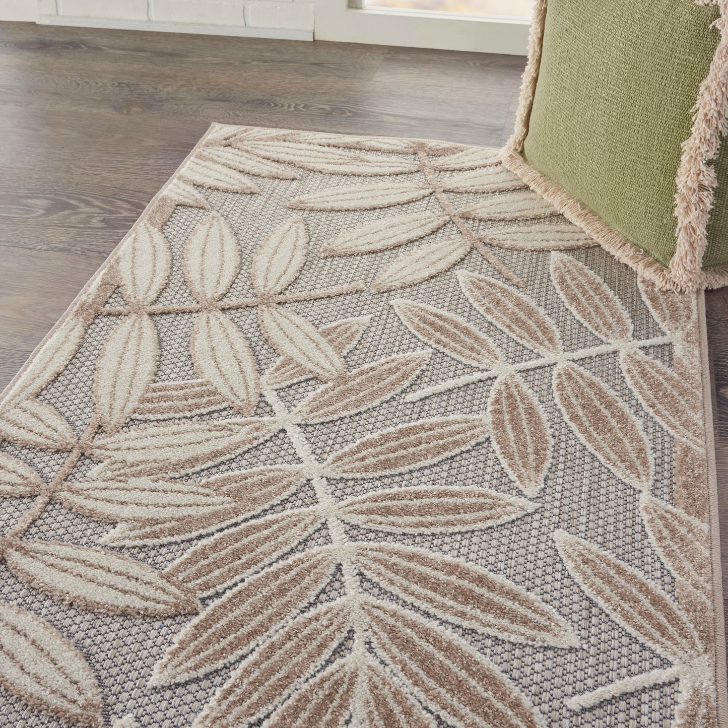 Neutral-toned area rug with beige leaf motif, woven texture on gray background; modern botanical style.