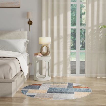 Bright bedroom with white bed, round blue-beige rug, white nightstand, lamp and books, sheer curtains by window.