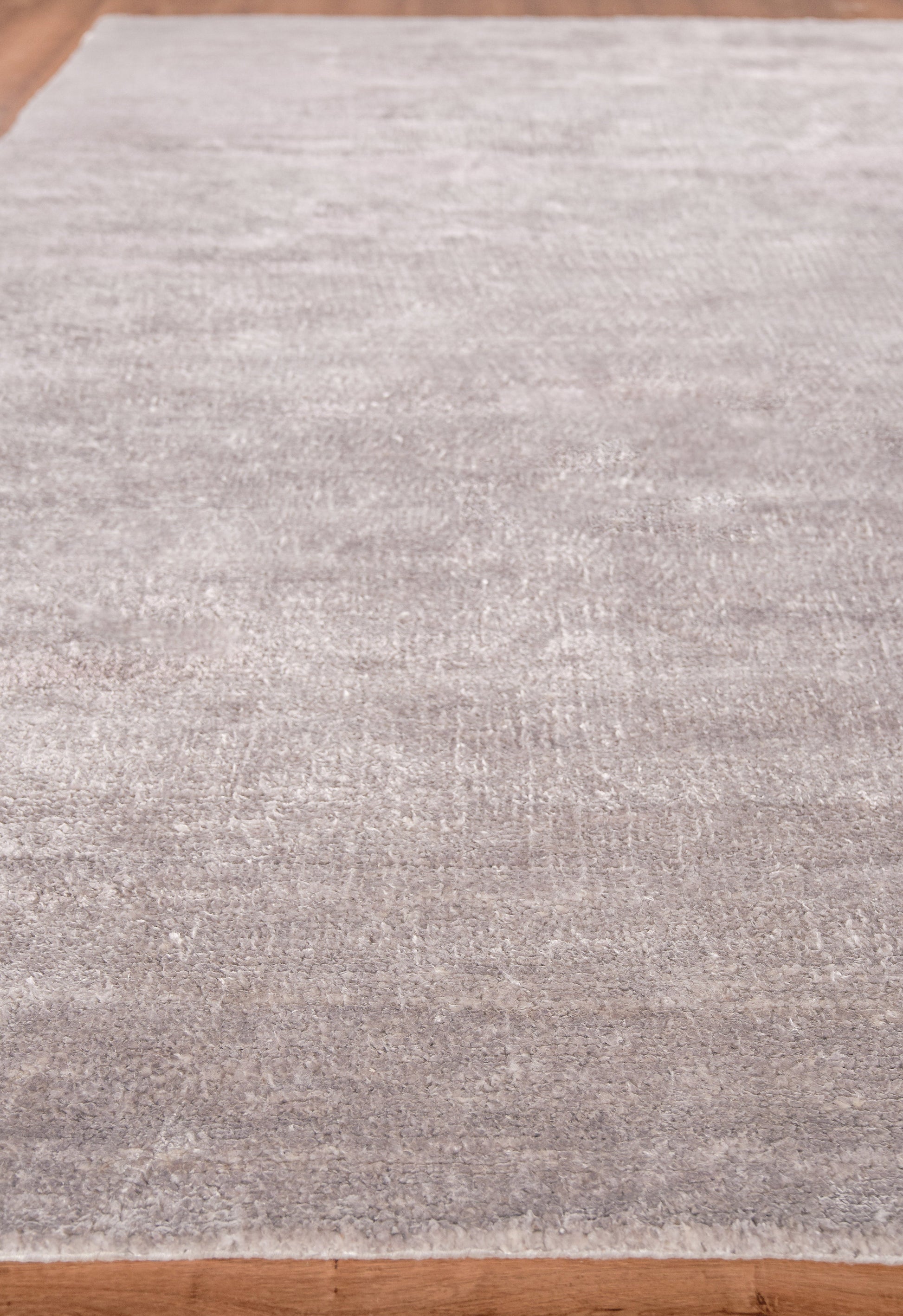 Light gray, low-pile rectangular area rug with subtle shading on a wood floor.