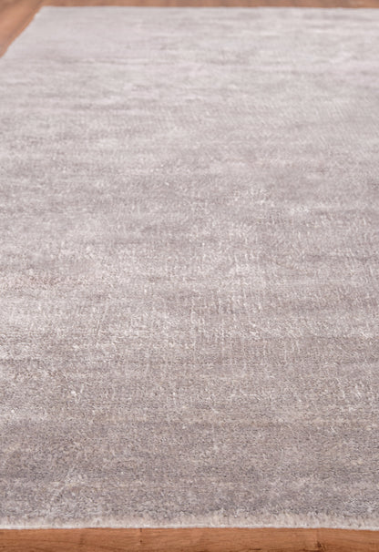 Light gray, low-pile rectangular area rug with subtle shading on a wood floor.