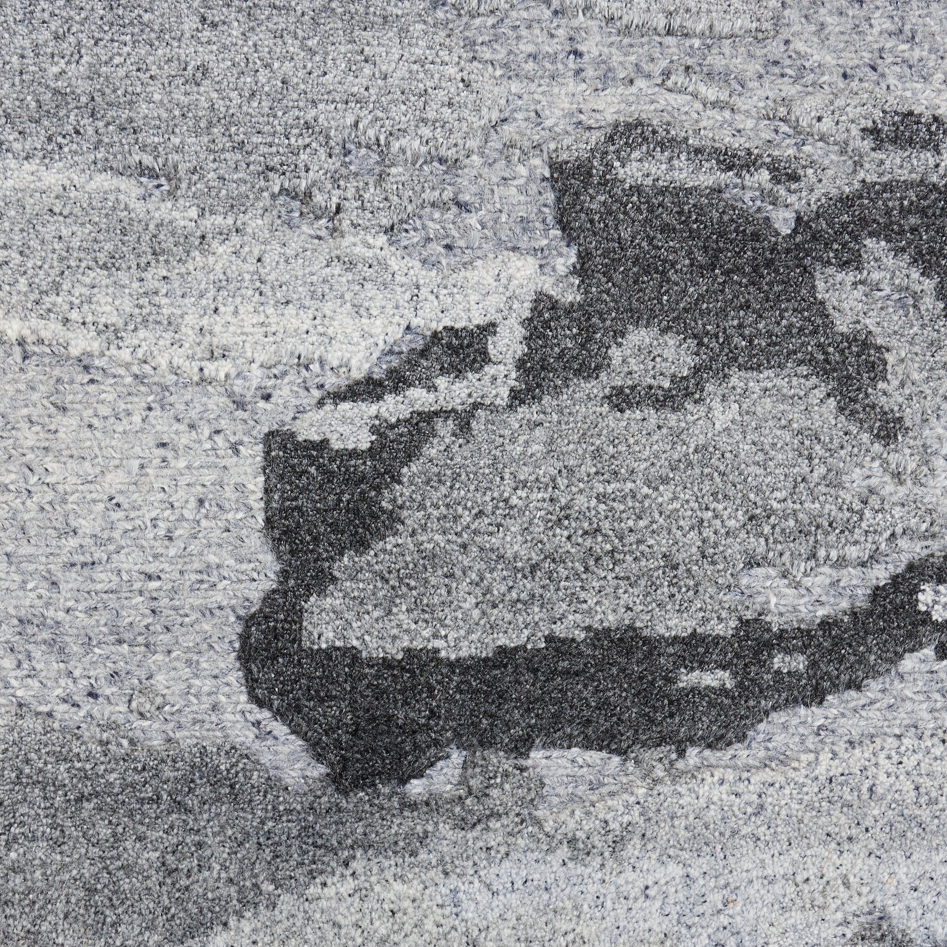 Close-up of gray abstract area rug with plush shag pile & a charcoal pattern.