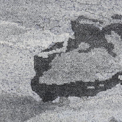 Close-up of gray abstract area rug with plush shag pile & a charcoal pattern.