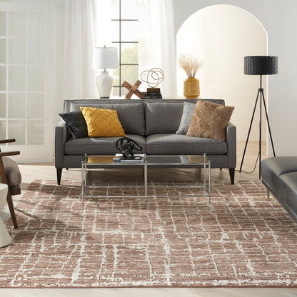 Gray sofa with yellow and tan cushions, glass coffee table, beige patterned rug, and modern decor in a bright living room.