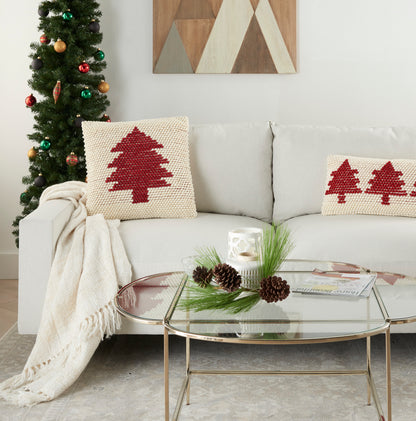 Cream sofa with red tree knitted pillows, beige throw, glass coffee table with pinecones, Christmas tree and wall art.