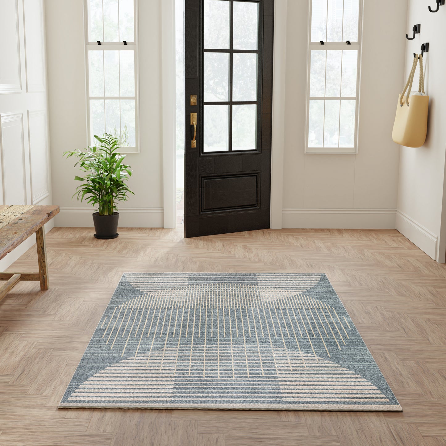 Blue geometric flat-weave area rug on light hardwood entryway floor; modern lines, ideal foyer decor.