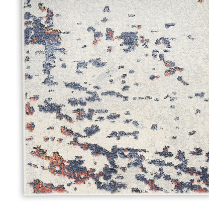Cream area rug with abstract navy blue and rust orange speckle pattern, woven textured look.