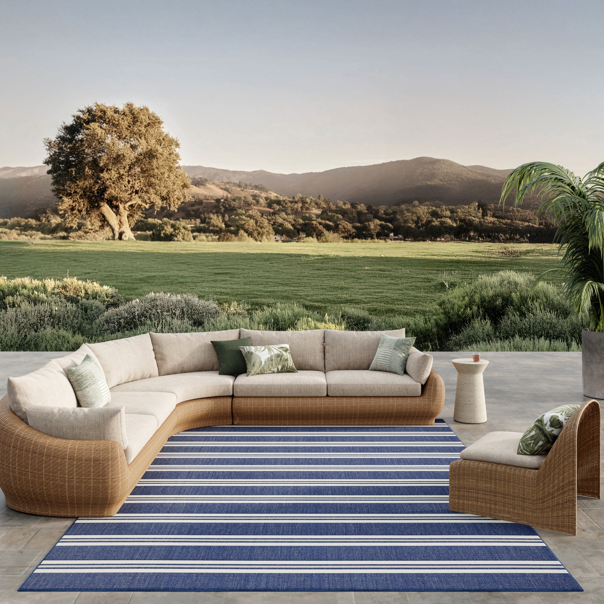 Modular outdoor rattan sectional with beige cushions on a blue striped rug, modern patio lounge.
